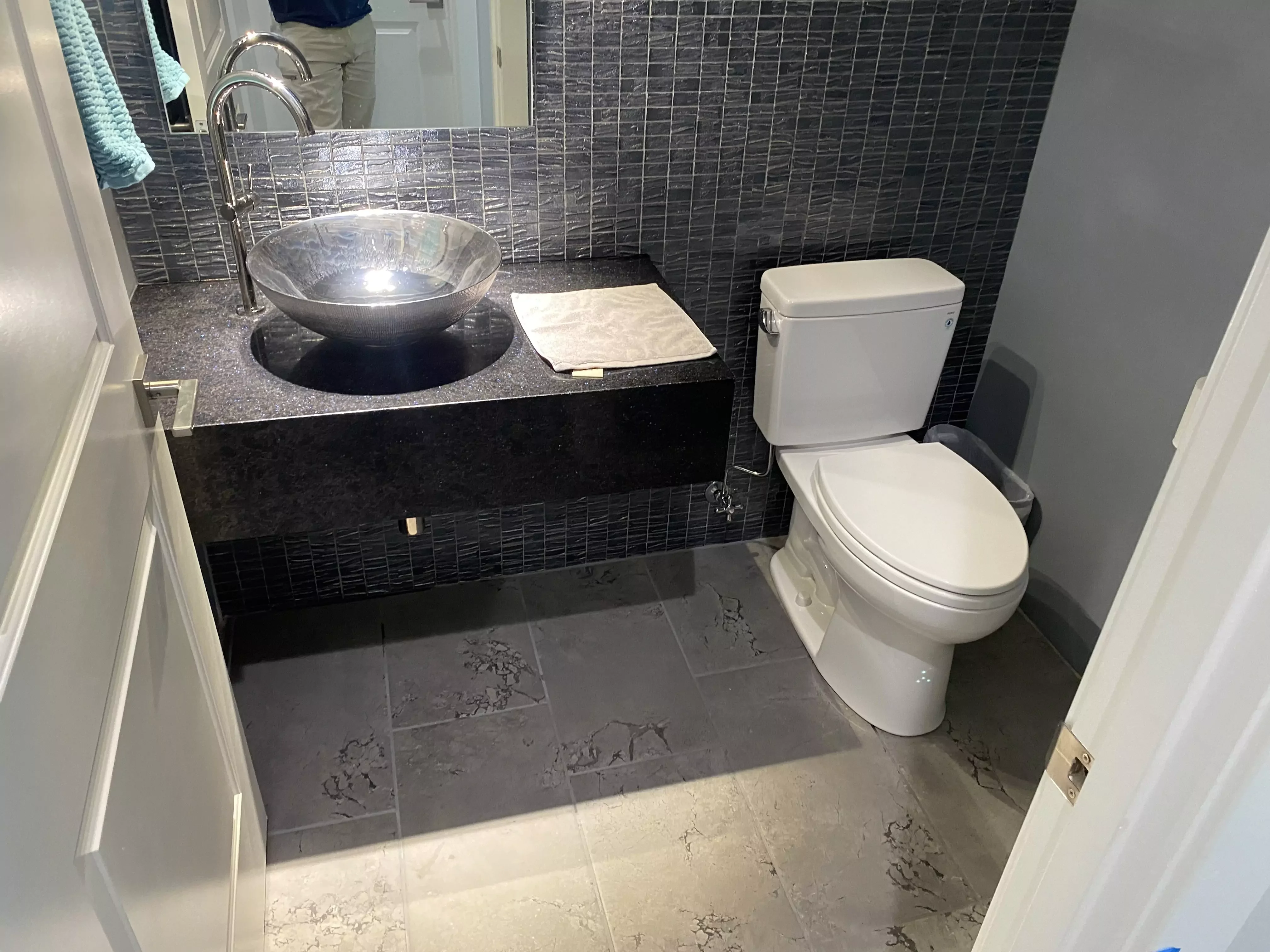 A newly installed bathroom with a vessel sink, faucet, and toilet in a modern tiled space.